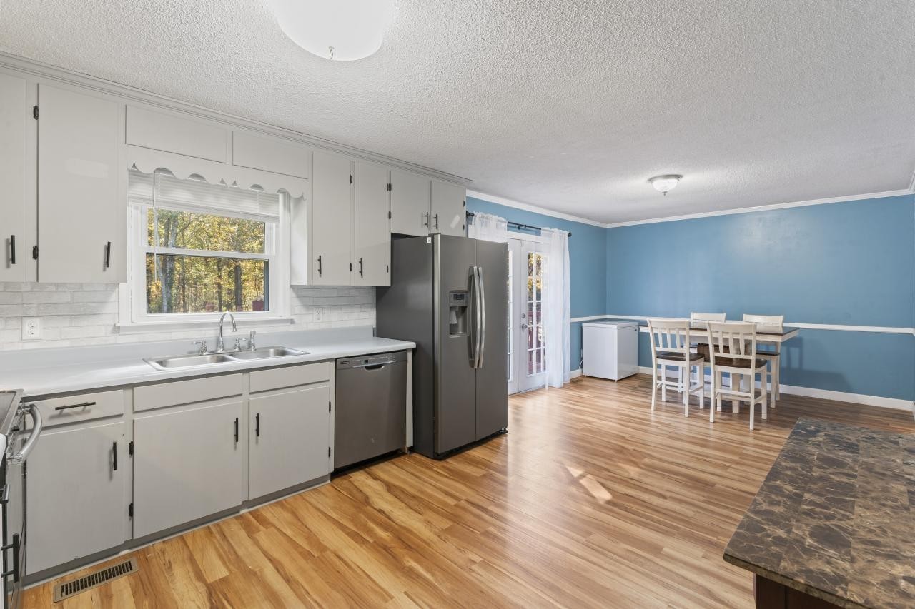 a kitchen with stainless steel appliances granite countertop a dining table chairs and a refrigerator