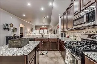 a kitchen with stainless steel appliances granite countertop a stove top oven a sink dishwasher and cabinets with wooden floor
