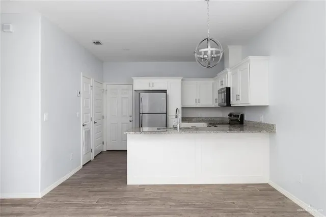 a view of kitchen with granite countertop stainless steel appliances a sink and a refrigerator