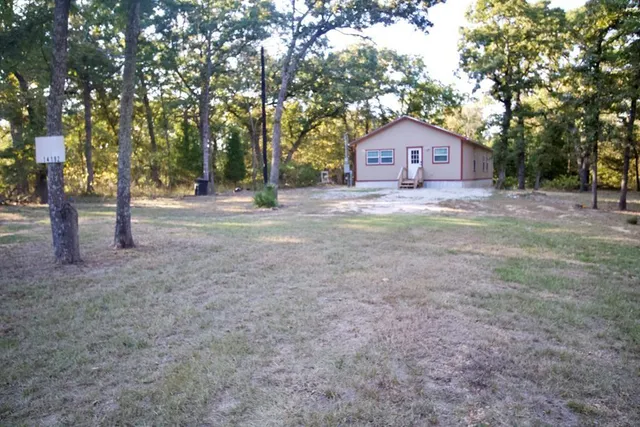 a wooden house with large trees and wooden fence