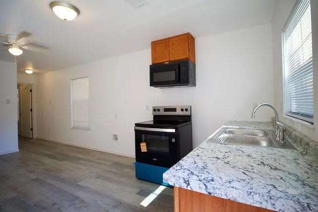 a kitchen with granite countertop a sink a stove and a microwave