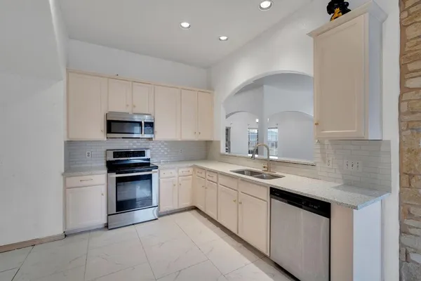 a kitchen with stainless steel appliances granite countertop a sink and dishwasher a stove top oven with white cabinets