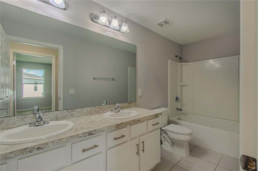 3470 Beau Road Kissimmee, FL 34746 - Photo 16 of 40 a bathroom with a granite countertop sink a toilet and a large mirror