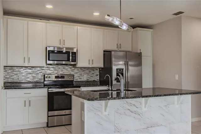 a kitchen with stainless steel appliances granite countertop a stove a sink and a refrigerator