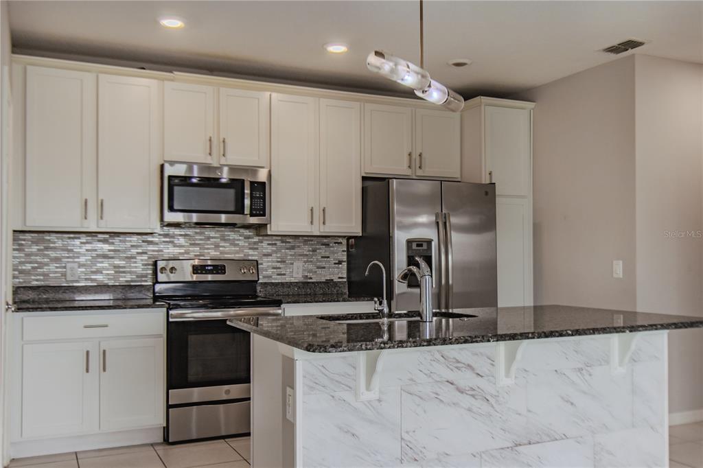 3470 Beau Road Kissimmee, FL 34746 - Photo 5 of 40 a kitchen with stainless steel appliances granite countertop a stove a sink and a refrigerator