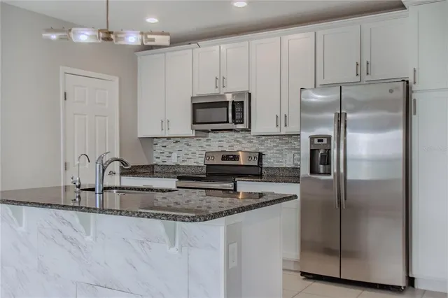 a kitchen with granite countertop a refrigerator sink and microwave