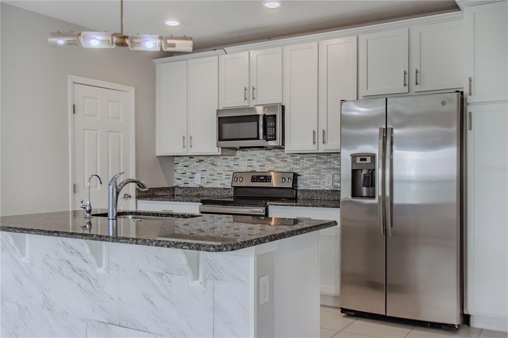 3470 Beau Road Kissimmee, FL 34746 - Photo 6 of 40 a kitchen with granite countertop a refrigerator sink and microwave