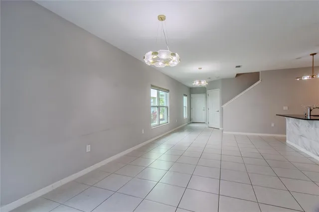 a view of an empty room with window and chandelier fan