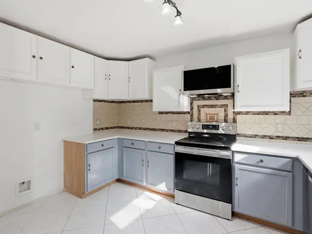 a kitchen with granite countertop white cabinets and stainless steel appliances