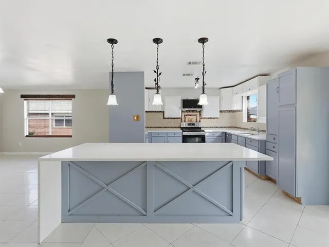 a kitchen with a sink a stove a refrigerator and white cabinets