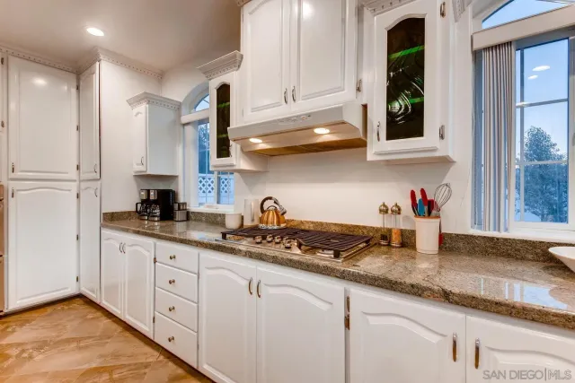 a kitchen with granite countertop a sink a stove and cabinets