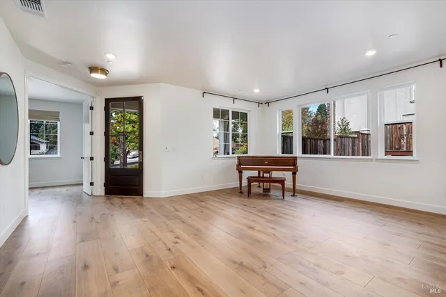 a large white kitchen with a stove a sink a refrigerator and white cabinets with wooden floor