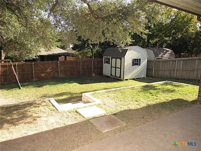 a view of backyard with small cabin and wooden fence