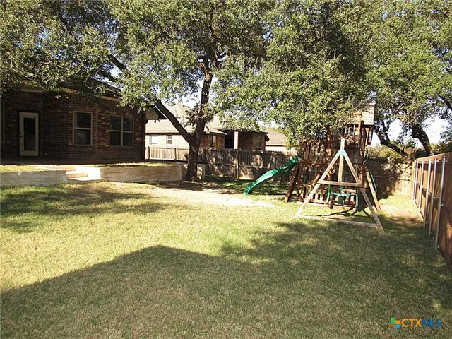 a view of a house with a yard and large tree