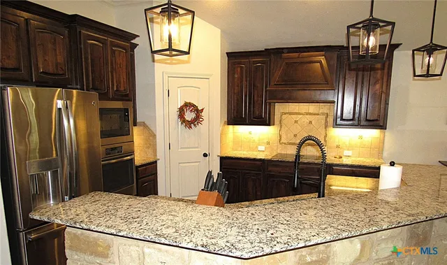 a kitchen with stainless steel appliances kitchen island granite countertop a refrigerator a stove and sink