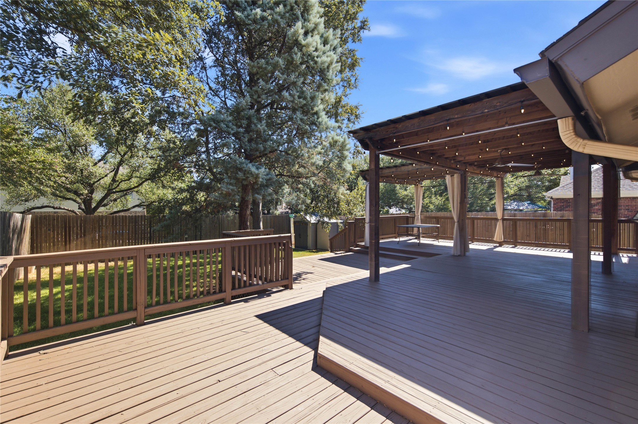 6032 Roxbury Lane Austin, TX 78739 - Photo 25 of 34 An expansive wooden deck with an integrated pergola overlooking a grassy, fenced yard.