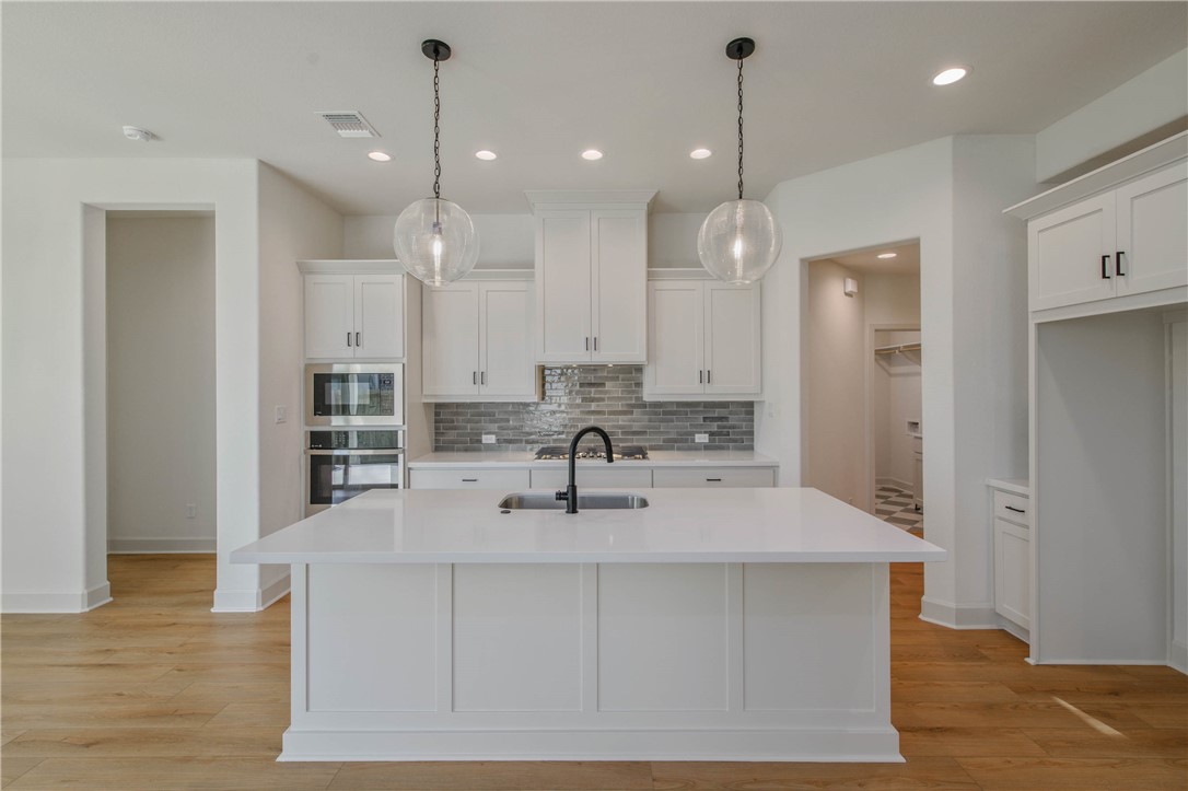 1652 Frontera Ranch Boulevard College Station, TX 77845 - Photo 10 of 29 a kitchen with kitchen island a sink stainless steel appliances and wooden floor