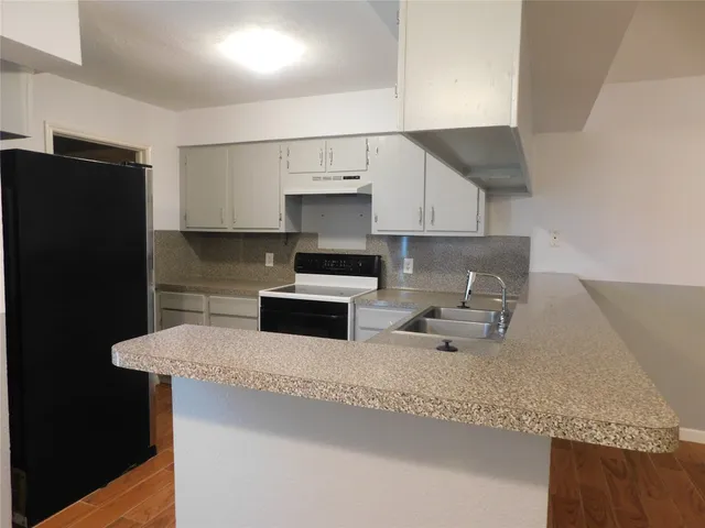 a kitchen with granite countertop a sink a stove and refrigerator