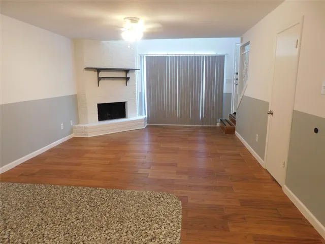 a view of a big room with wooden floor and fireplace