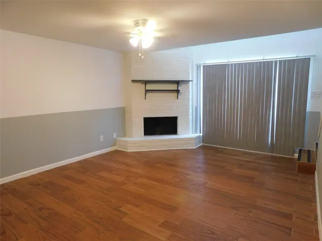 an empty room with windows fireplace and fan