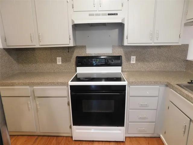 a kitchen with granite countertop white cabinets and white appliances