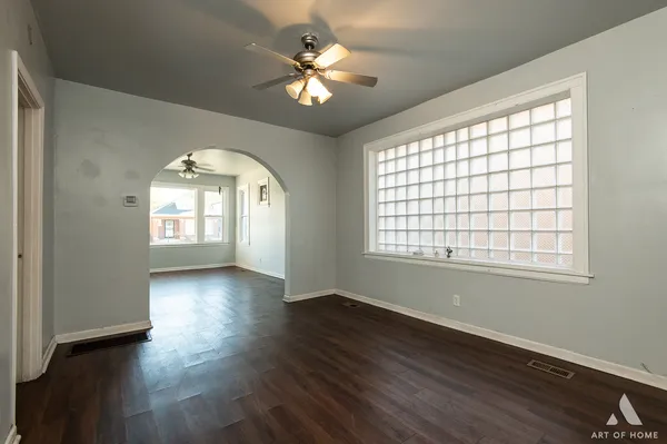a view of empty room with wooden floor and fan