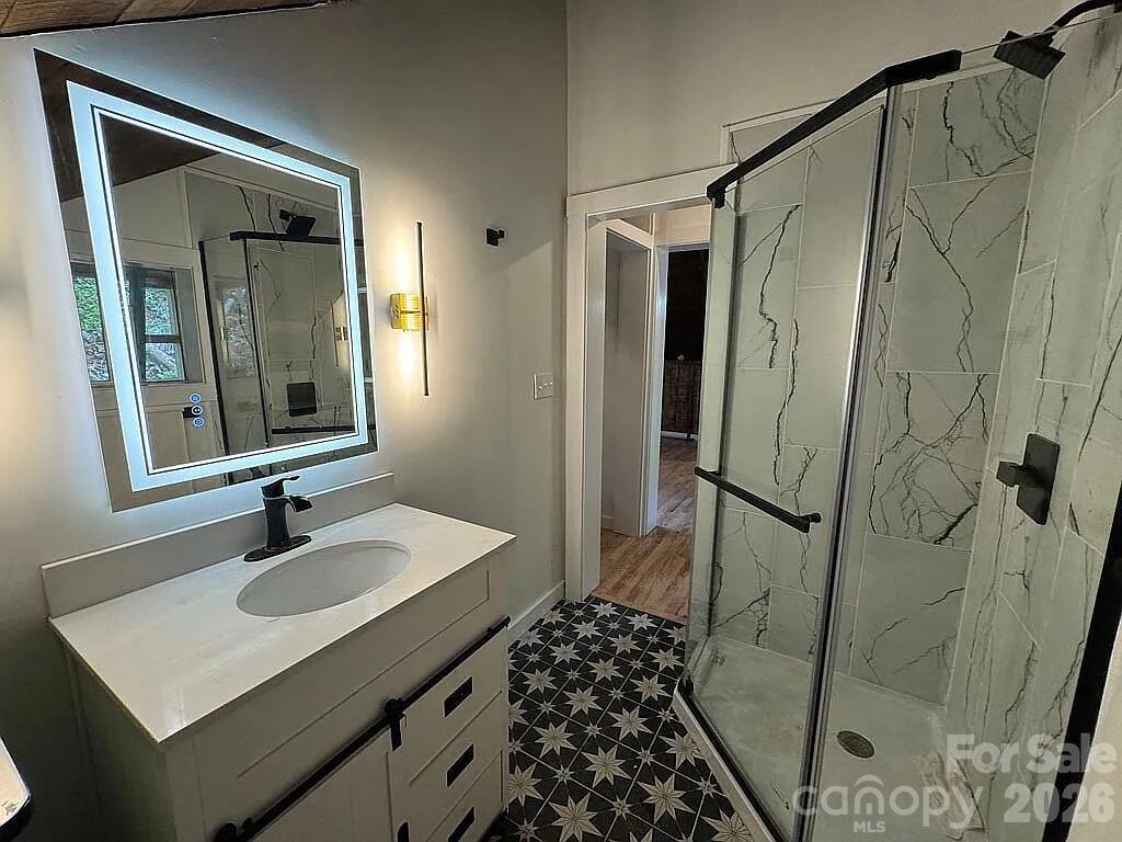 101 Mountain Farm Road Burnsville, NC 28714 - Photo 24 of 32 a bathroom with a sink a mirror a vanity and shower