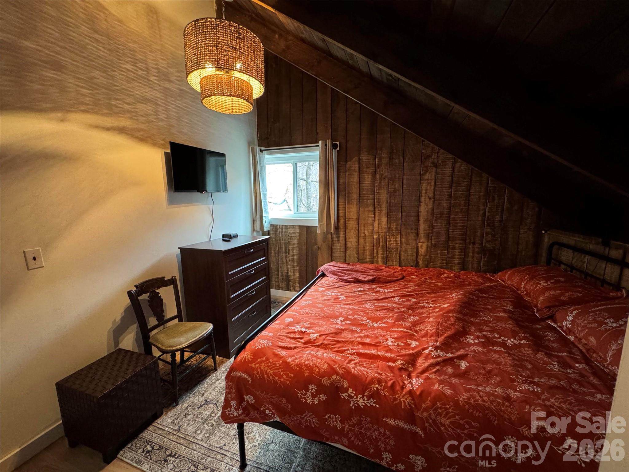 101 Mountain Farm Road Burnsville, NC 28714 - Photo 27 of 32 a bedroom with a bed and a chandelier