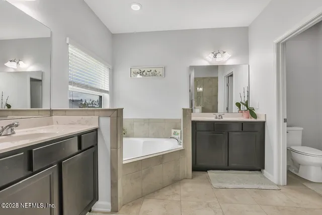 a spacious bathroom with a tub sink and mirror