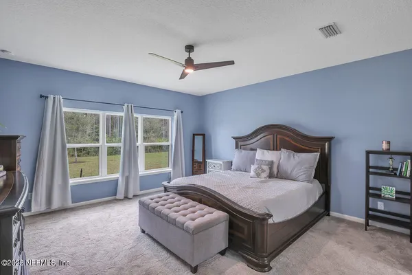 a spacious bedroom with a bed a table and large window