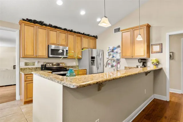 a kitchen with stainless steel appliances a sink dishwasher a refrigerator a stove a oven with white cabinets and wooden floor