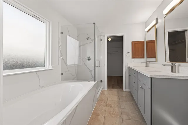 a spacious bathroom with a tub sink a mirror and a shower