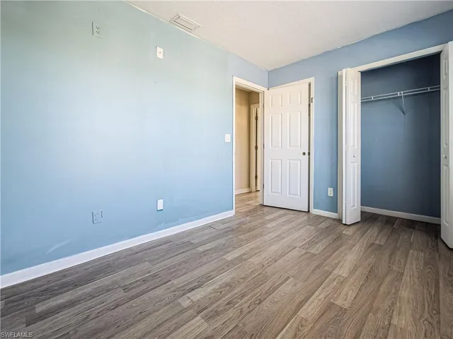 a view of an empty room with wooden floor and closet