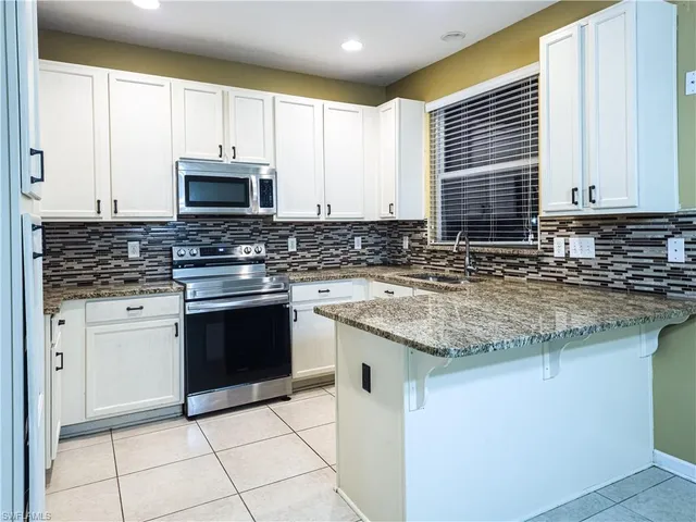 a kitchen with stainless steel appliances granite countertop a sink a stove a microwave and cabinets
