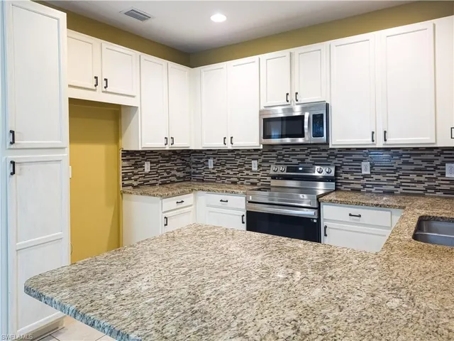 a kitchen with stainless steel appliances granite countertop a stove a sink and a microwave