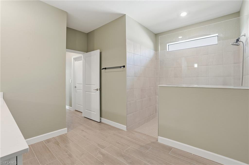 19306 Hinkley Drive Estero, FL 33928 - Photo 17 of 49 an empty room with wooden floor and a bathroom