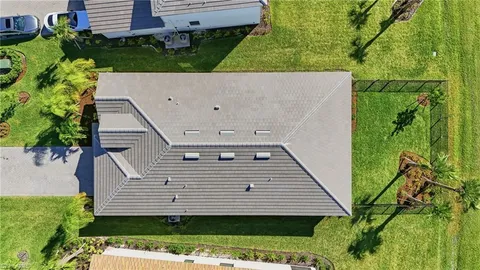 a view of a house with a big yard potted plants and palm trees