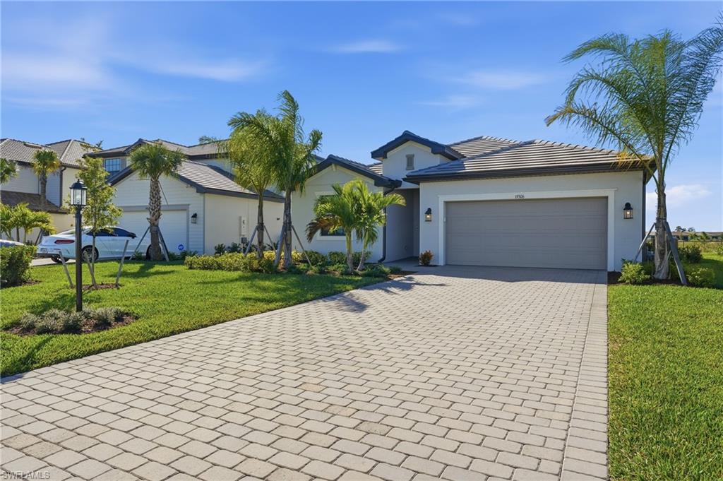 19306 Hinkley Drive Estero, FL 33928 - Photo 31 of 49 a view of a white house with a small yard and a large tree