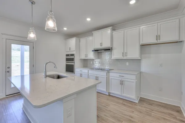 a kitchen with kitchen island granite countertop a sink cabinets and wooden floor