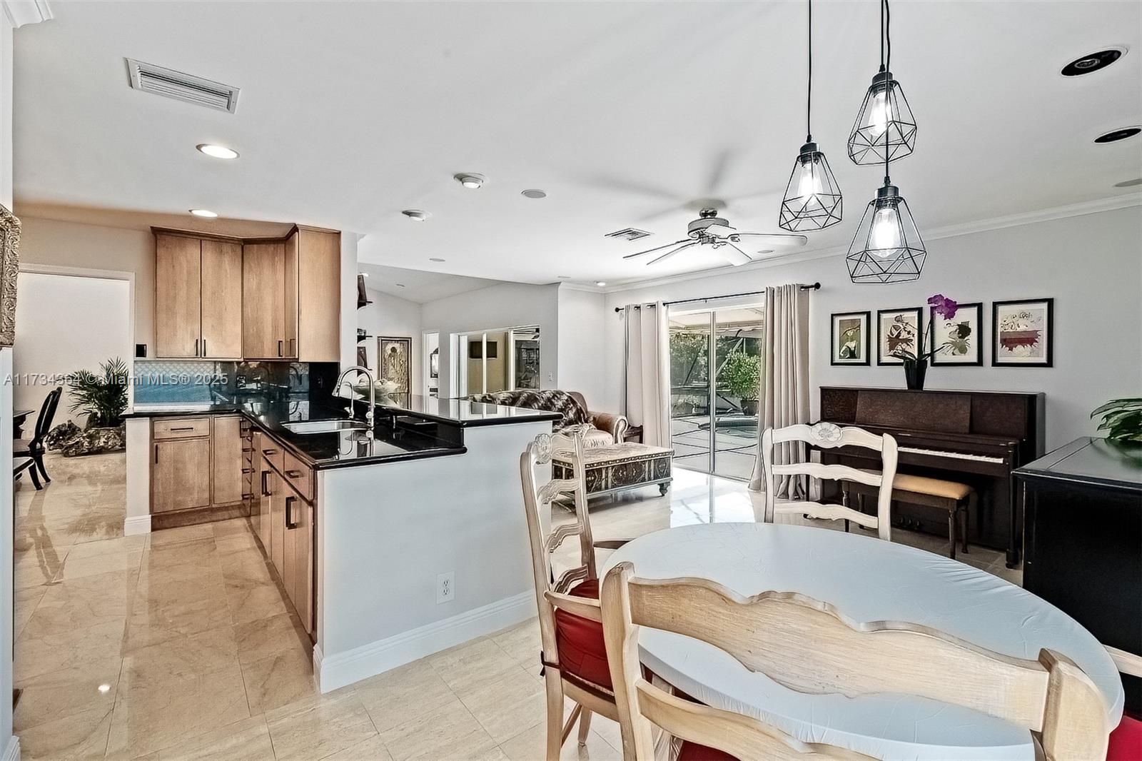 7260 Northwest 4th Avenue Boca Raton, FL 33487 - Photo 18 of 59 a kitchen with stainless steel appliances kitchen island granite countertop a stove a refrigerator a kitchen island a dining table and chairs with wooden floor