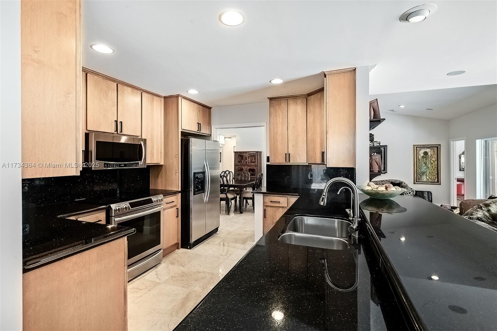 7260 Northwest 4th Avenue Boca Raton, FL 33487 - Photo 19 of 59 a kitchen with stainless steel appliances a sink a stove cabinets and a dining table
