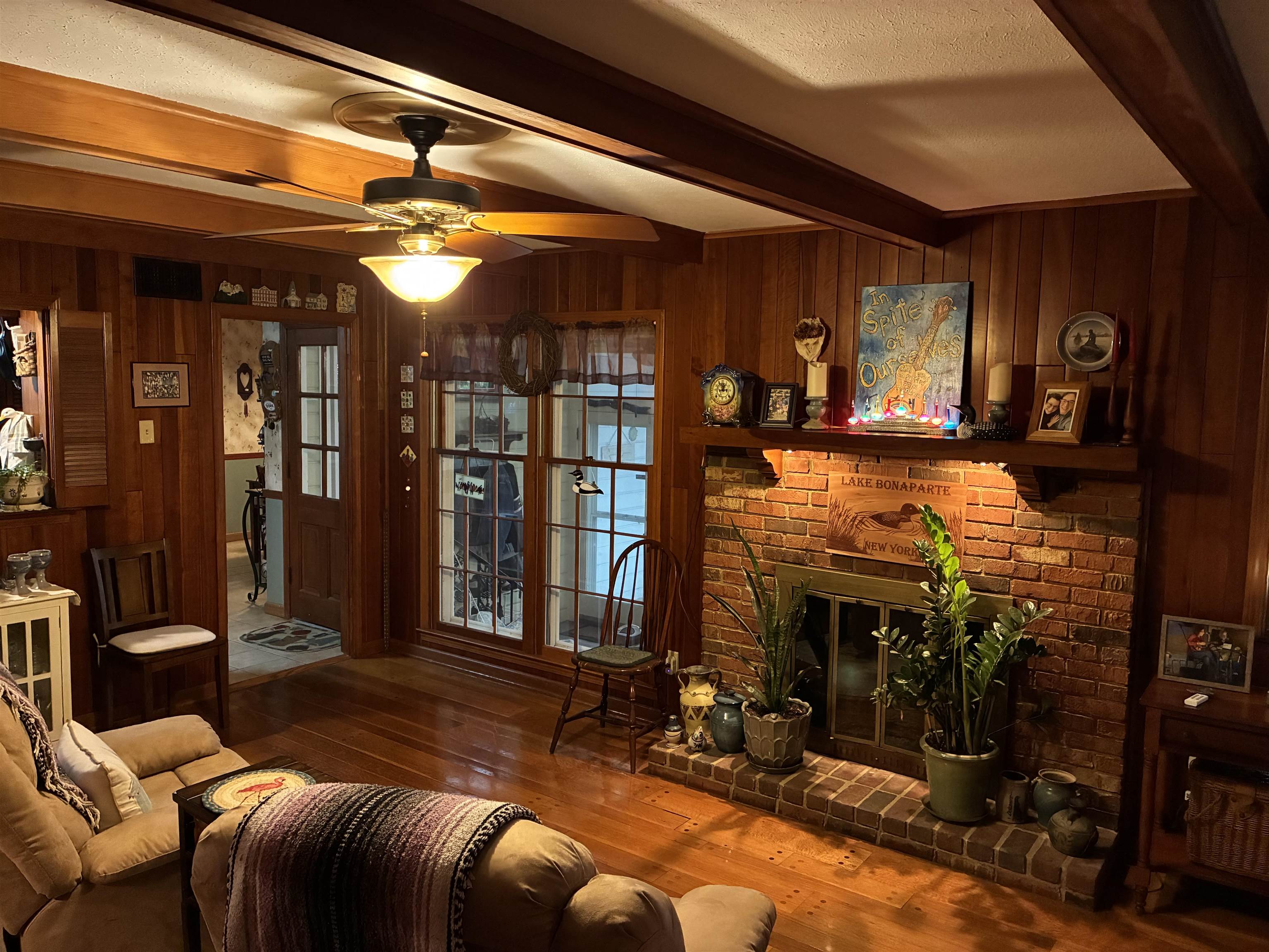 3194 Lammermuir Road Memphis, TN 38128 - Photo 16 of 40 Brick-faced fireplace with a wood mantel, paneled walls, wood-finish flooring, exposed ceiling beams, and a ceiling fan with integrated lighting