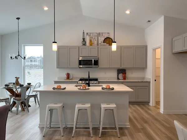 a kitchen with stainless steel appliances granite countertop a stove a refrigerator a sink a dining table and chairs with wooden floor