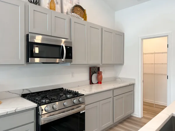 a kitchen with stainless steel appliances granite countertop white cabinets a stove top oven and dishwasher