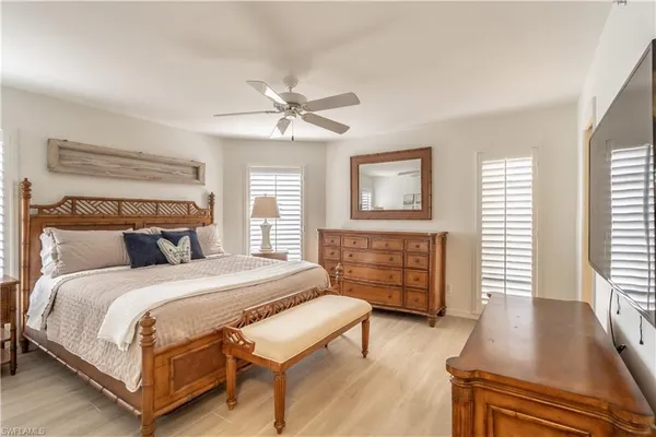 a bedroom with a bed a dresser and wooden floor