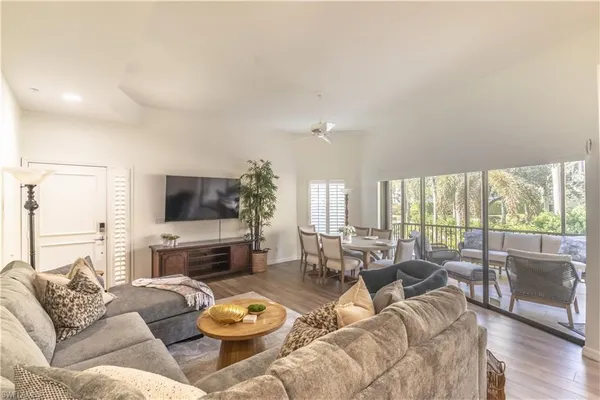 a living room with furniture a flat screen tv and a large window