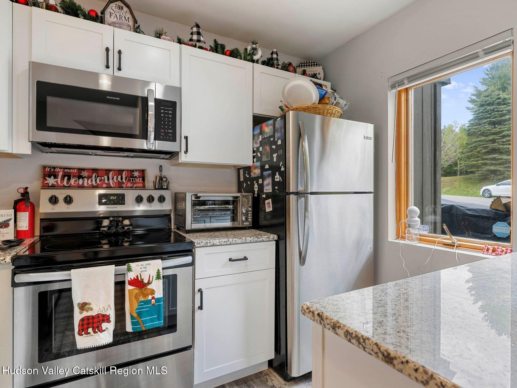 55 Windham Ridge Road, Unit 15H Windham, NY 12496 - Photo 11 of 34 a kitchen with stainless steel appliances granite countertop a refrigerator oven a stove a sink and a microwave