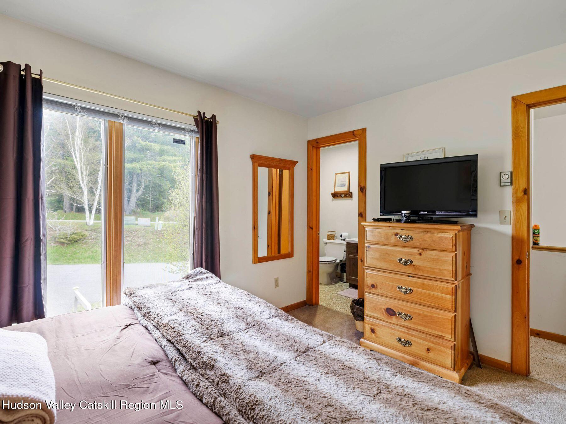 55 Windham Ridge Road, Unit 15H Windham, NY 12496 - Photo 21 of 34 a bedroom with a bed and flat screen tv