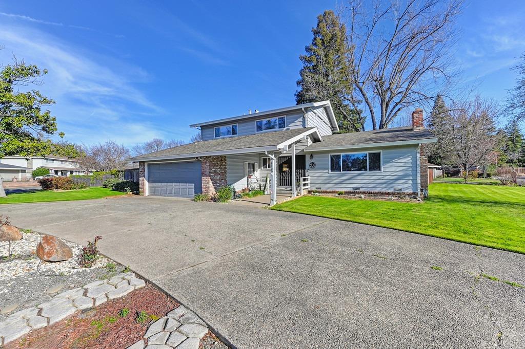 a view of a house with a yard and large tree