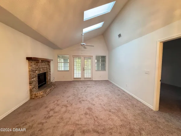 an empty room with windows and fireplace
